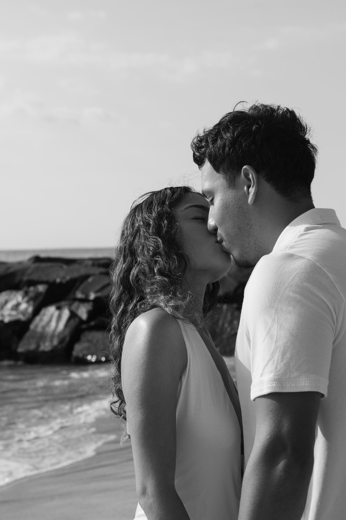Black and white portrait of a couple kissing on the beach