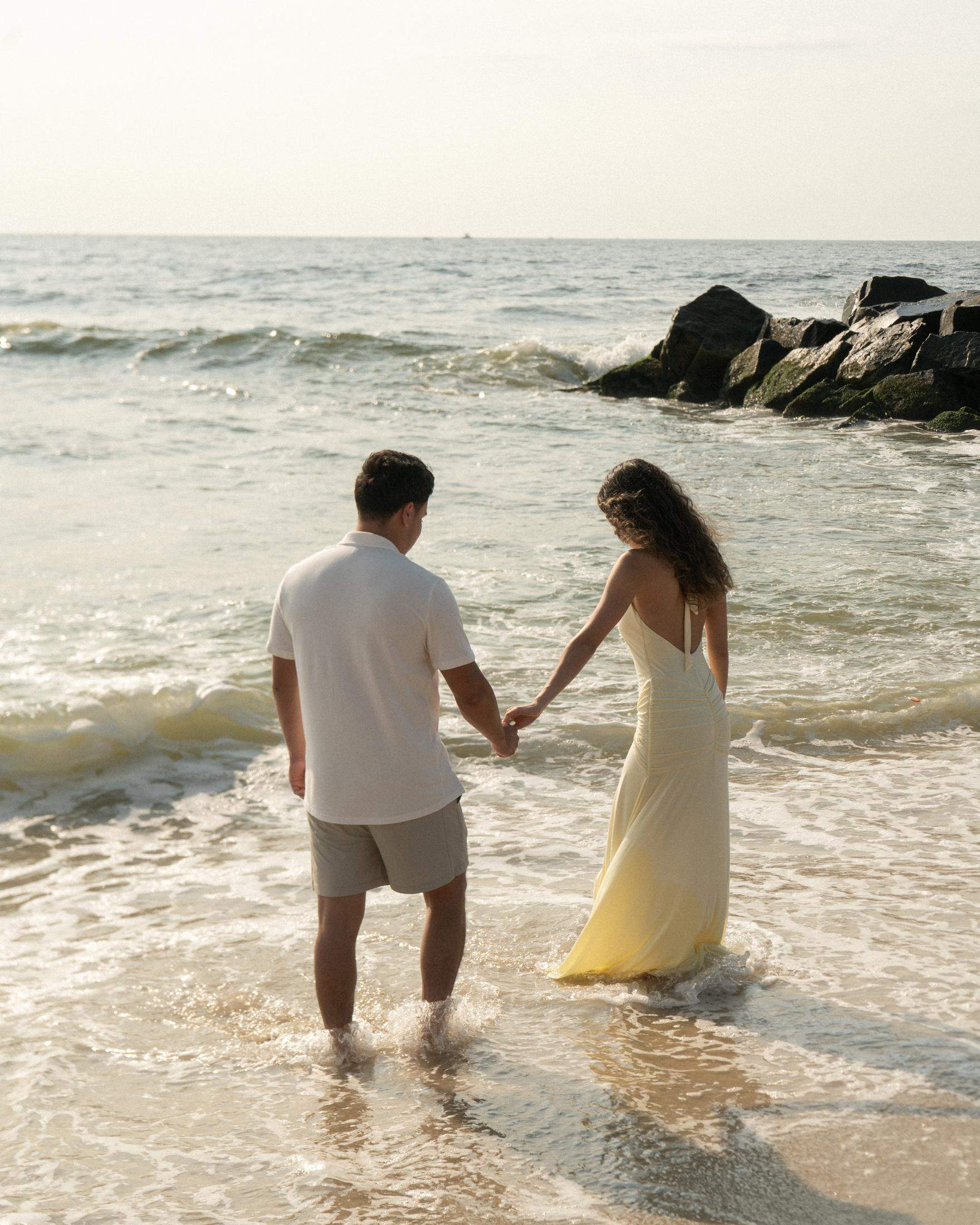 Couple walking hand in hand through ocean waves